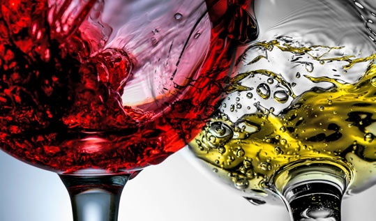 Exreme close up of red and white wine glasses, swirling.