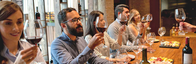 Wine Club members at a wine tasting room discussing a red wine.